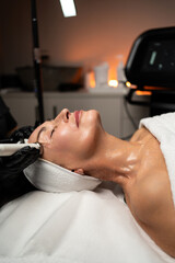 Radiofrequency facial lifting procedure for mature skin performed on an elderly woman in a modern beauty clinic.