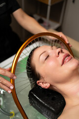 Luxury wellness experience featuring a woman during a calming scalp and hair treatment with water flow.