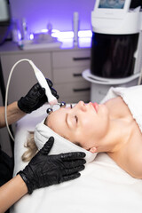Professional facial RF lifting procedure performed by a cosmetologist using modern radiofrequency equipment in a beauty clinic.