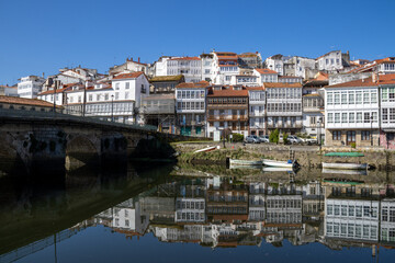 Obraz premium Scenic view from Praza a Enrique Ivntiga Eira Vella, Betanzos, Galicia, with riverside white homes and boats reflecting on the peaceful Mandeo River. 