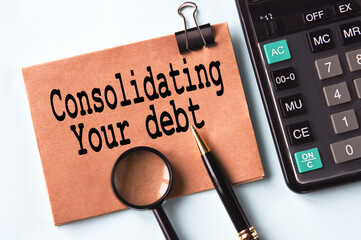 CONSOLIDATING YOUR DEBT - words on a brown sheet on the background of a calculator