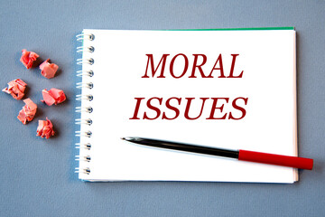 MORAL ISSUES - words in a notebook on a gray background with a pen.