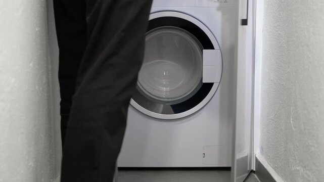 Closing white cabinet doors to hide washing machine. Minimalist interior design showing a person closing white cabinet doors to neatly conceal a washing machine, showcasing a clever solution