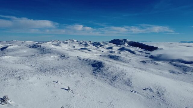 Vast snow covered mountain plateau under blue sky aeral winter landscape