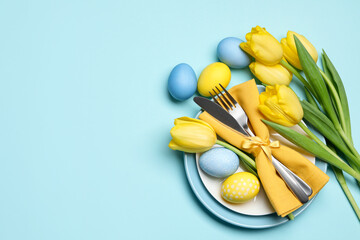 Easter celebration. Festive table setting with tulip flowers and painted eggs on light blue...