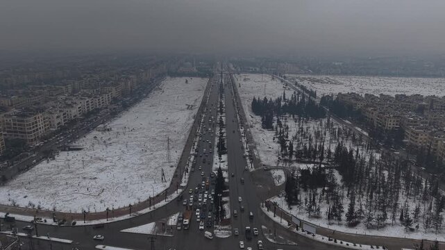 A drone shot of Aleppo, Syria, during a heavy snowstorm shows urban architecture and streets covered in white. Cinematic winter scenery in a Middle Eastern urban environment.