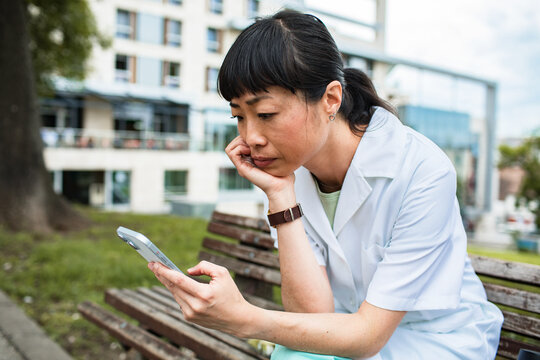 Nurse checking phone during break outside hospital