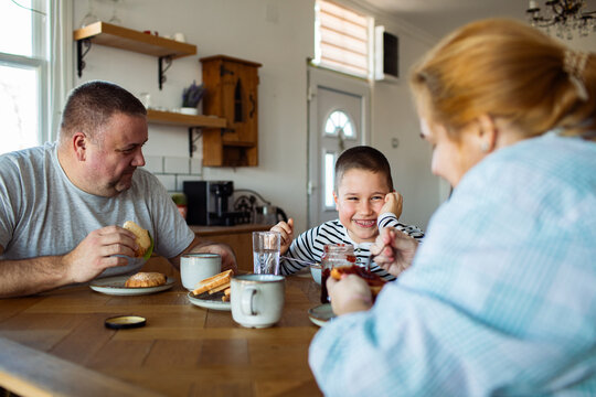 Parents and son eating breakfast at home kitchen
