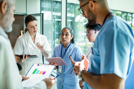 Doctors and nurses team huddle discussing patient care in hospital