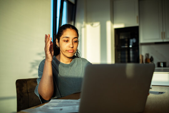 Young woman frustrated on video call at home kitchen