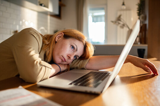 Tired woman resting on laptop at home workspace