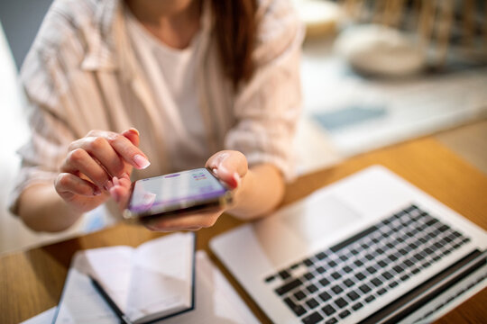 Young woman using smartphone at home office desk