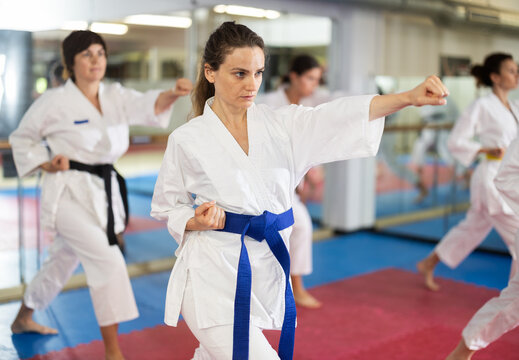Group of women in kimonos train karate techniques in studio