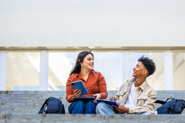 University students collaborating on project outdoors using tablet and notebook