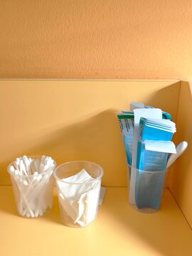 Cotton swabs, wipes and spatulas in plastic cups on a shelf