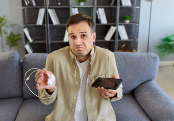 Charger smartphone phone cable has charging problem. A puzzled confused man inspects a faulty...
