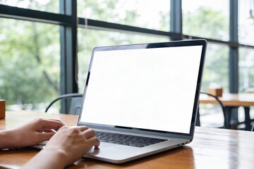Hands typing on a modern metallic laptop computer with large blank white screen mockup in a coffee shop for remote work concept.