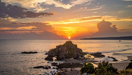Obraz premium Stunning sunset over the ocean, rocks, and clouds.