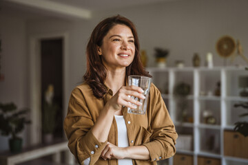 Woman smiling holding glass of water for hydration