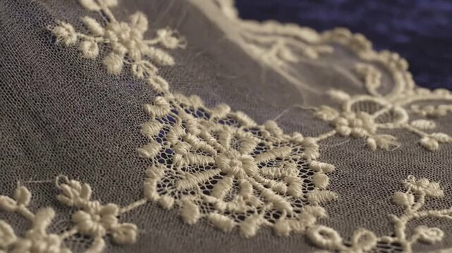 Intricate beige lace fabric with floral patterns on brown cloth.