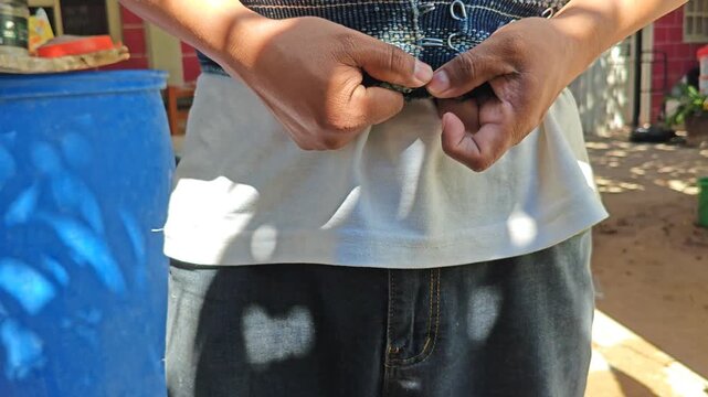 Young man processing bamboo with traditional tools: cutting, cleaning and making slats with axe and machete.