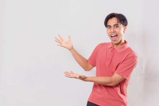 a smiling young adult man gesturing with open hands while presenting copy space. Isolated on white background, suitable for advertising, promotion, presentation, and marketing content.
