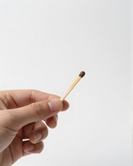 Close-Up of a Hand Holding a Single Matchstick Against a White Background