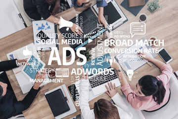 A diverse group of professionals engaged in a collaborative business meeting, discussing marketing strategies and analyzing digital advertising data on laptops. Tessel