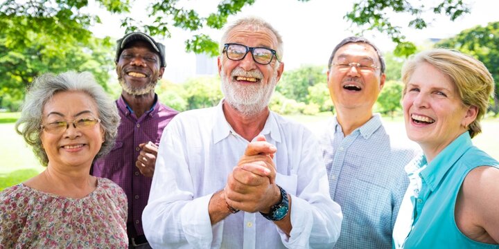 Group of diverse elderly people smiling outdoors. Seniors enjoying nature, laughing together. Happy elderly friends in a park, diverse and joyful gathering. Diverse elderly people outdoors.