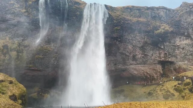 Static Shot of Tourists Walking Towards Seljalandsfoss Waterfall, Iceland.