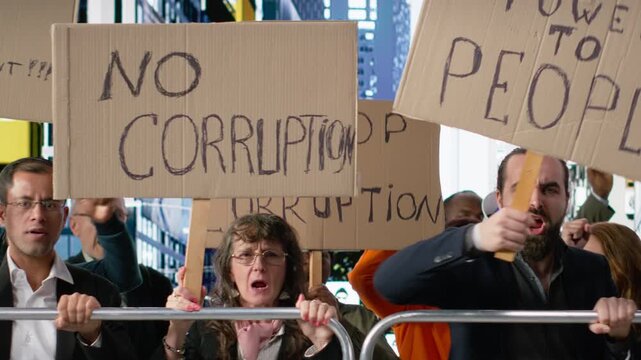 Warring crowd of activists chanting against corruption and political misconduct, holding banners and posters asking to stop corruption, wanting public accountability and democracy. Camera B.