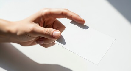 Hand holding blank white card on surface
