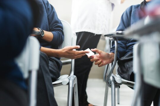 Students discreetly passing notes in a classroom. Note passing among students, a common classroom scene. Engaged students exchanging notes during class. Cheating on exams.