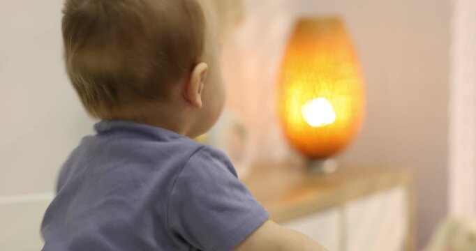 Cute little baby with wooden rattle in crib at home. Camera moving forward