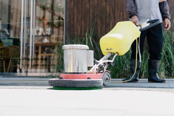 The janitor is cleaning the floor with a floor scrubber.