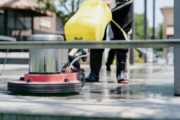 The janitor is cleaning the floor with a floor scrubber