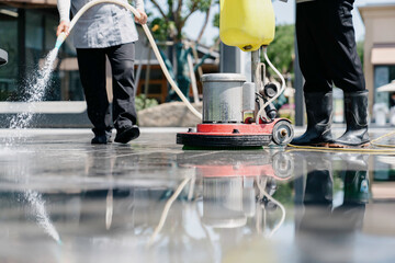 The janitor is cleaning the floor with a floor scrubber.