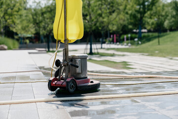 The janitor is cleaning the floor with a floor scrubber.
