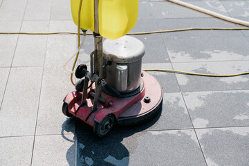 The janitor is cleaning the floor with a floor scrubber