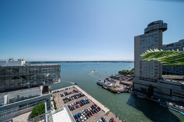 Obraz premium Elevated view of toronto waterfront and harbor on a sunny summer day, boats navigating lake ontario beside high rise city skyline, marina and busy parking lot visible
