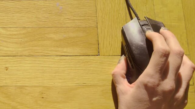 A close-up shot of a hand actively scrolling the wheel on a computer mouse against a wooden texture. This footage represents digital research, web navigation, and focused online browsing activity.