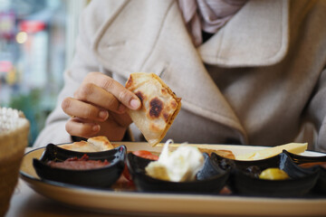 Person holding a piece of flat bred while sitting at a table