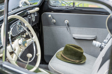 A vintage car with a green hat on the seat