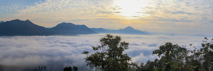 A panoramic view of a sea of ​​clouds and mountains at sunrise.