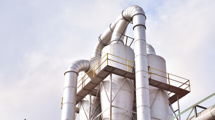 Large steel silos connected by curved pipelines form a rigid industrial composition, emphasizing function, scale, and mechanical precision © Alexander Dennis RE