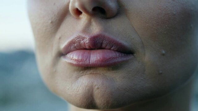 Close-up of a woman's lips and chin with subtle facial features.