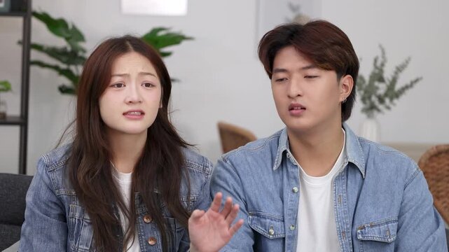 Young Asian Couple Reacting with Disgust and Worry in Living Room