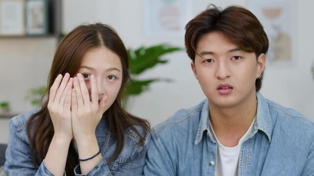 Young Asian Couple Reacting with Fear While Watching a Scary Movie