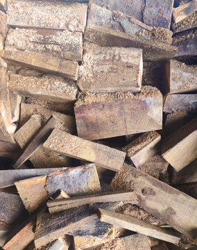 Close-up of rough cut wooden blocks stacked tightly, covered with sawdust and raw textures, representing forestry materials, woodworking processes, and natural construction resources