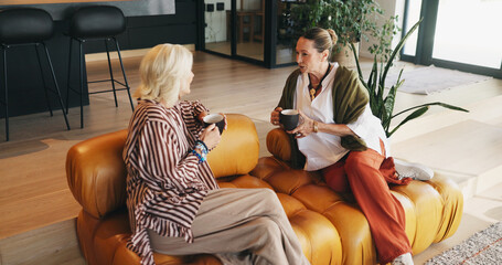 Friends, women and conversation with coffee on couch, storytelling and weekend visit for...